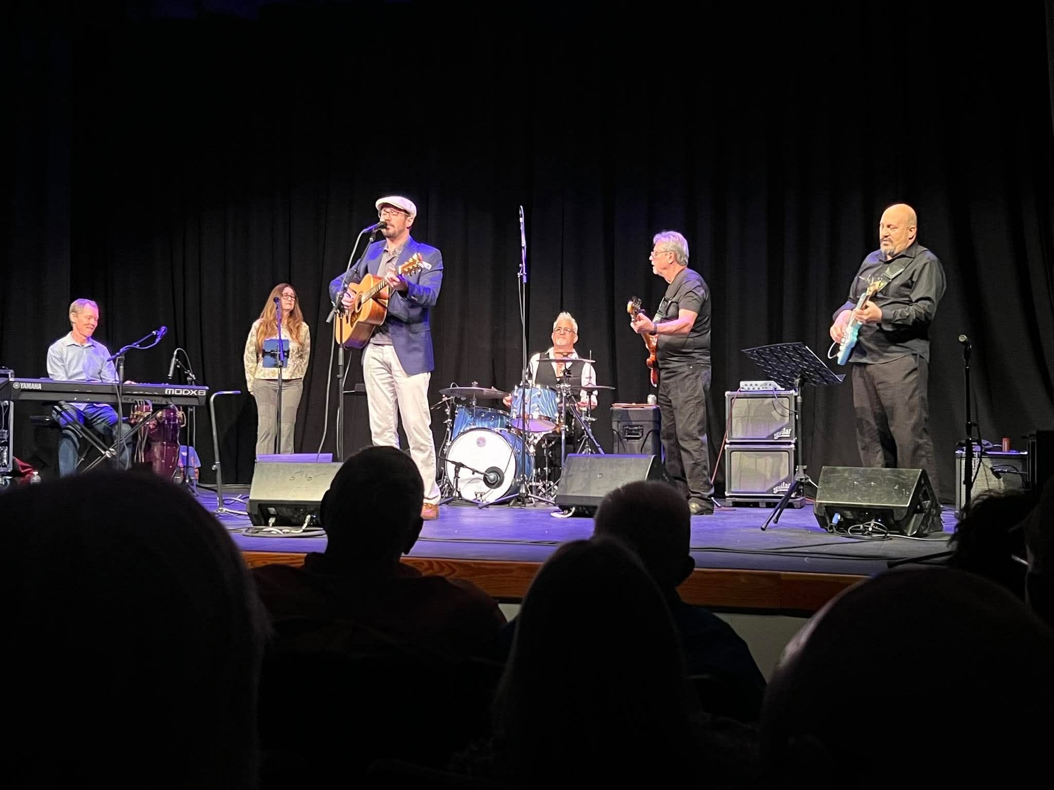 The St Pete Collective on stage under blue light, Joey Interrante on drums at center